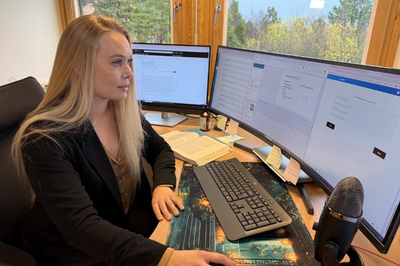 kvinne med langt blondt hår jobber foran en pc på et kontor